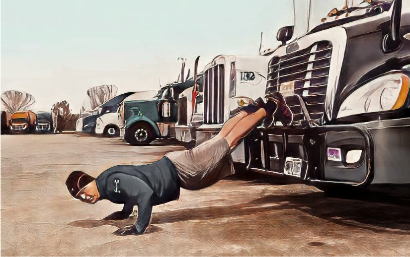 man doing push ups in a parking lot, his feet pressed against the grille of his semi truck. 